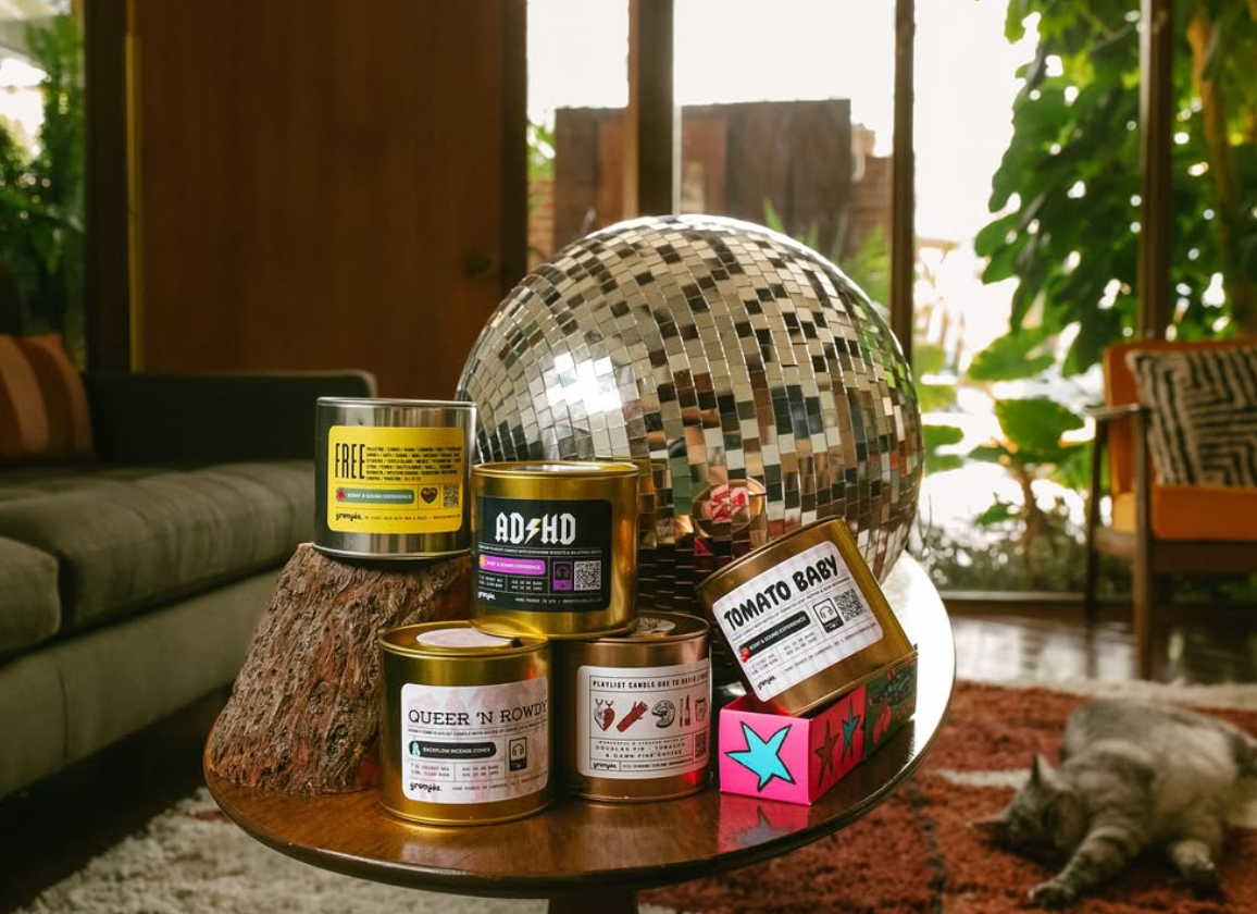 Collection of playlist candles  and a disco ball on a table with a cat in the background